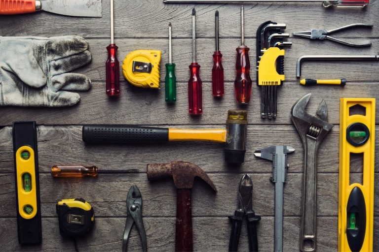A wooden table displaying a variety of tools, including wrenches, screwdrivers, and pliers, arranged neatly.